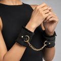 Luxury black faux leather wrist cuffs with soft plush lining connected by a detachable gold-tone chain.